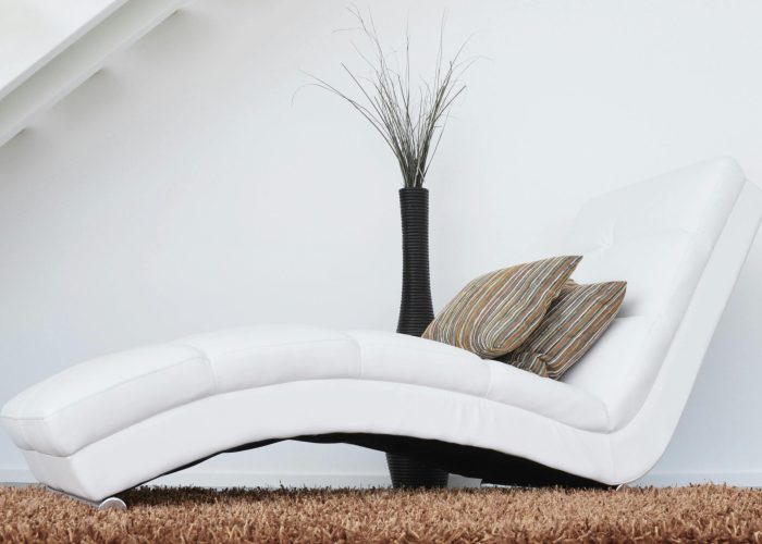Elegant white lounge chair with cushions on plush carpet, perfect for relaxation.